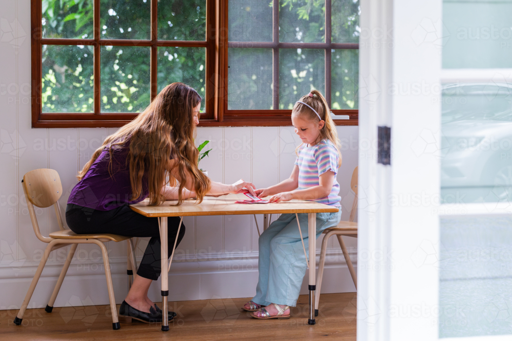 Speech pathologist working with young girl using word flash cards for language development - Australian Stock Image