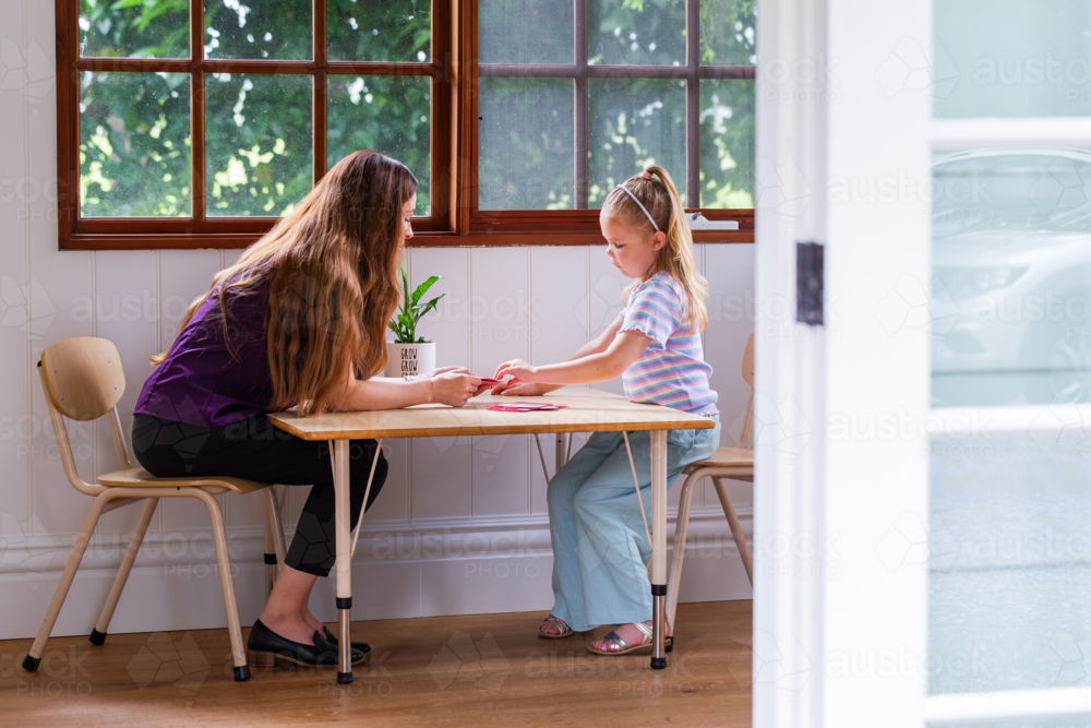 Speech pathologist working with young girl using word flash cards for language development - Australian Stock Image