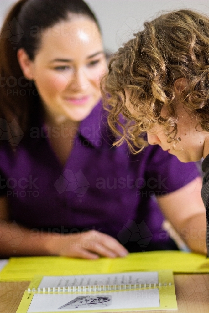 Speech therapist assessing child in clinic as boy reads - Australian Stock Image
