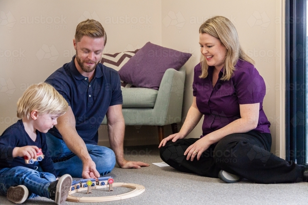 Speech therapist speaking with parent of child as boy plays with toy - Australian Stock Image