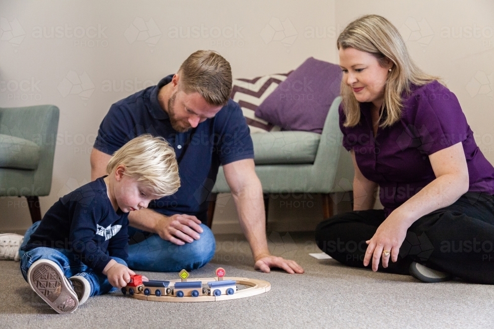 Speech therapist speaking with parent of child as boy plays with toy - Australian Stock Image