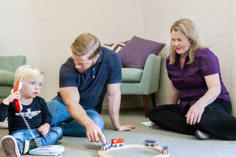 Speech therapist speaking with parent of child as boy plays with toy - Australian Stock Image