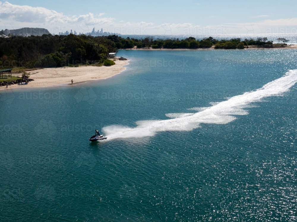 Speeding Jet Ski leaving a white trail in clear blue water - Australian Stock Image