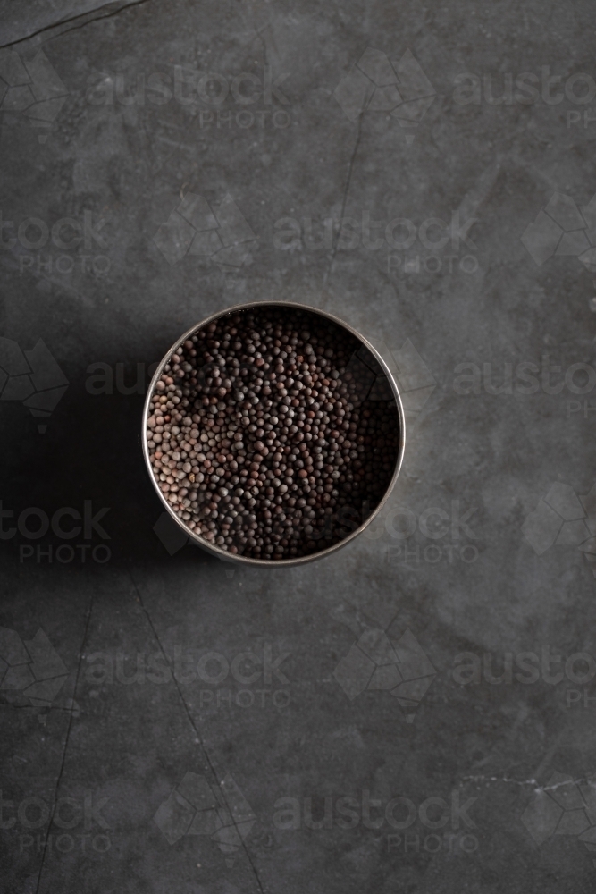 Spice tin of black mustard seeds on a dark marble background - Australian Stock Image