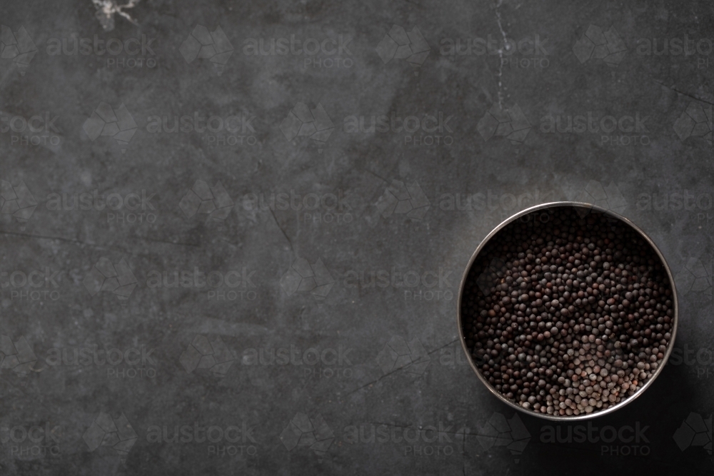 Spice tin of black mustard seeds on a dark marble background - Australian Stock Image
