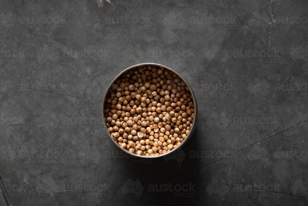 Spice tin of coriander seeds on dark marble background - Australian Stock Image