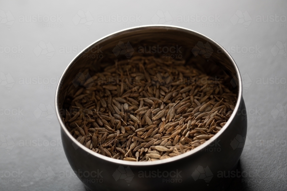 Spice tin of cumin seeds on dark marble background - Australian Stock Image