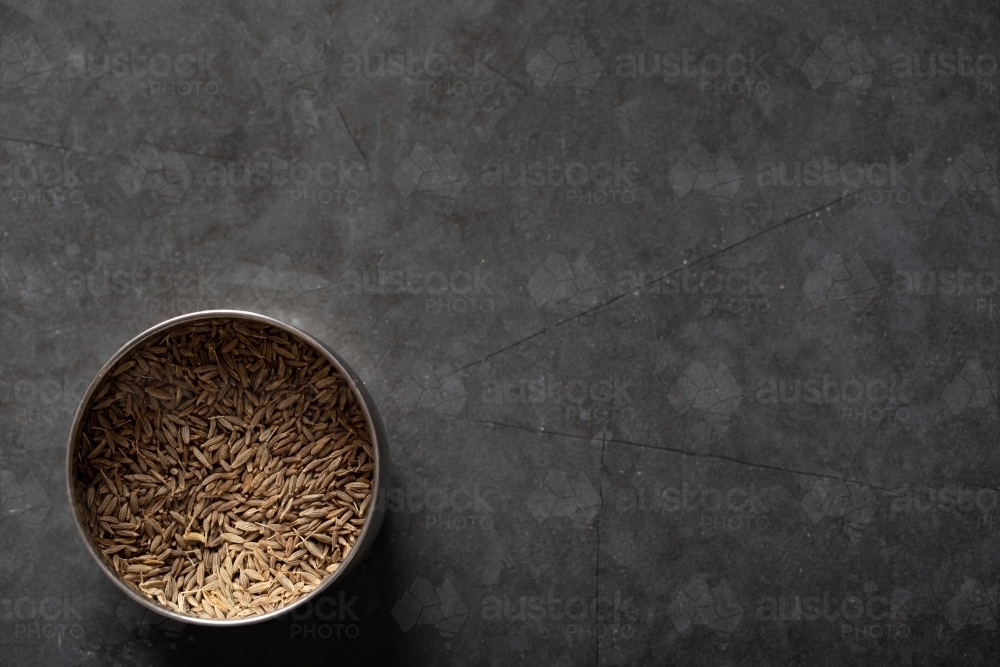 Spice tin of cumin seeds on dark marble background - Australian Stock Image