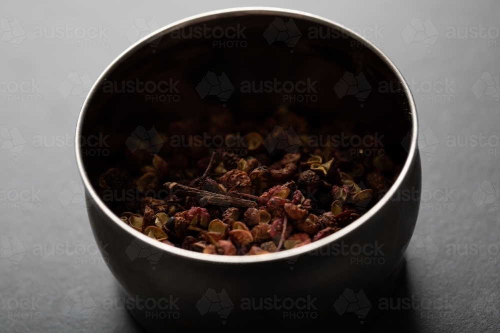 Spice tin of Sichuan pepper on dark marble background - Australian Stock Image