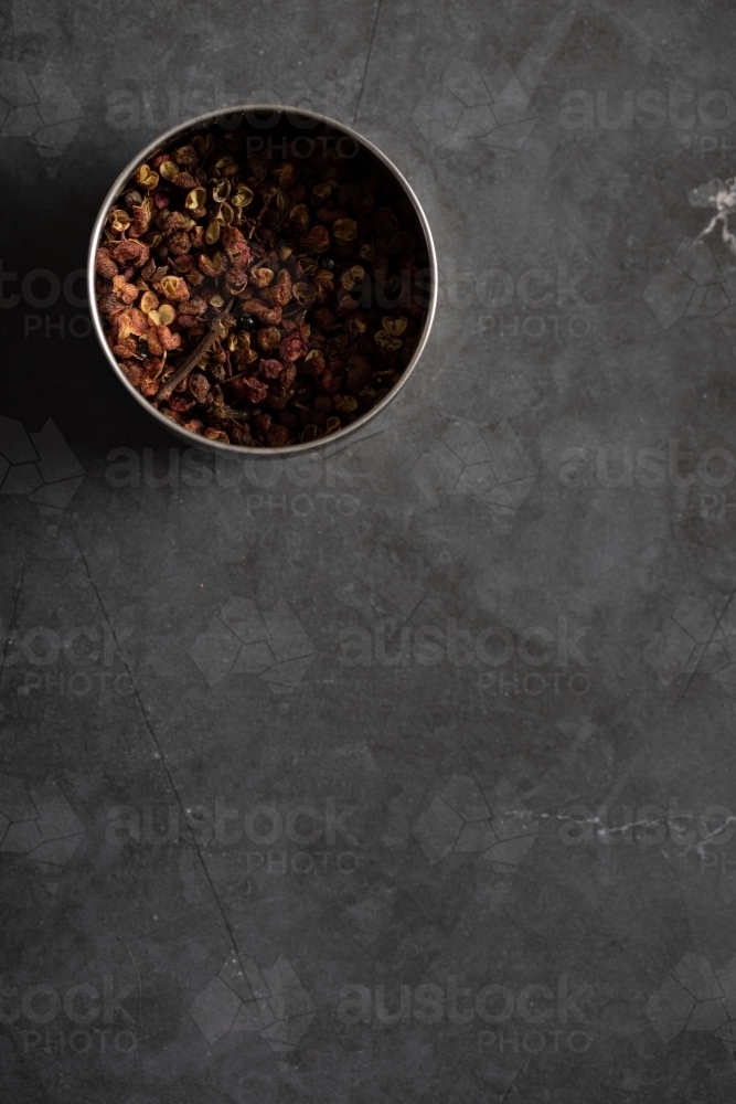 Spice tin of Sichuan pepper on dark marble background - Australian Stock Image