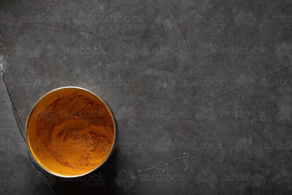 Spice tin of turmeric on dark marble table - Australian Stock Image
