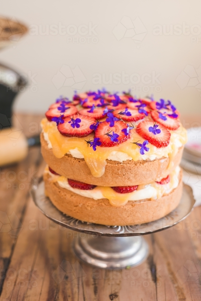 sponge cake with lemon curd, strawberries and edible flowers - Australian Stock Image