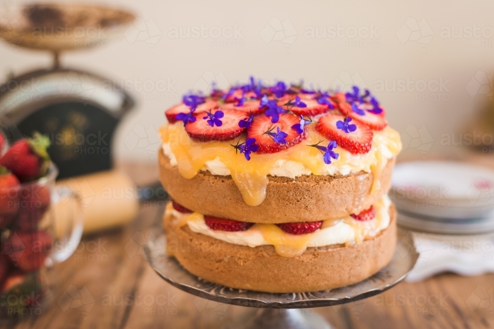 sponge cake with lemon curd, strawberries and edible flowers - Australian Stock Image