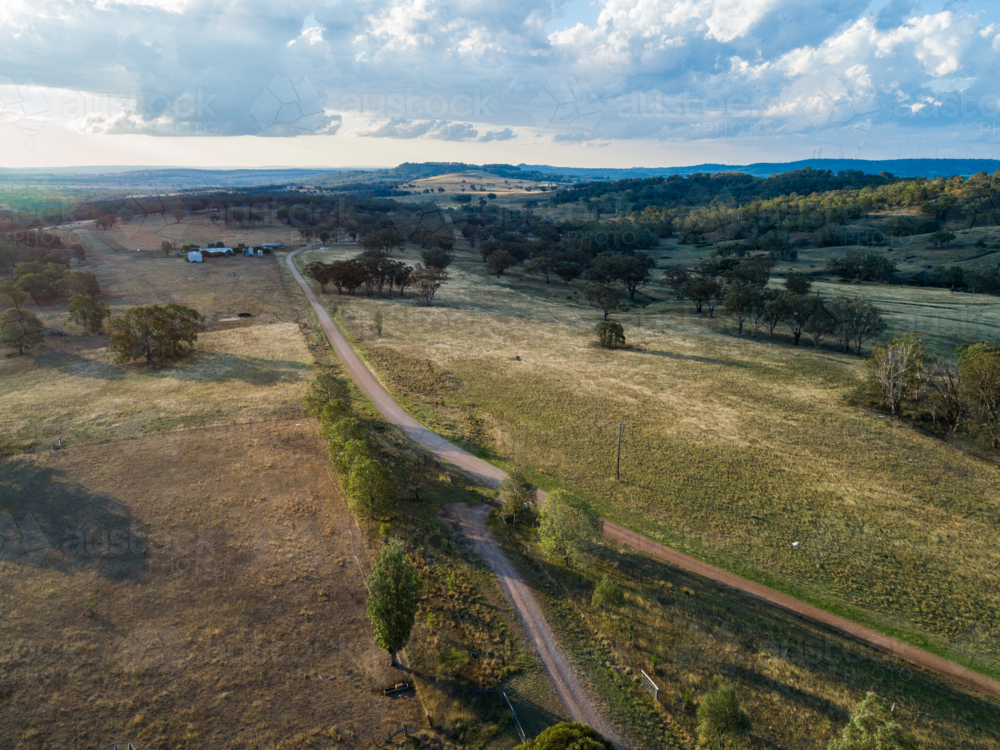 Spring mountain road a gravel road winding through paddocks of farmland - Australian Stock Image