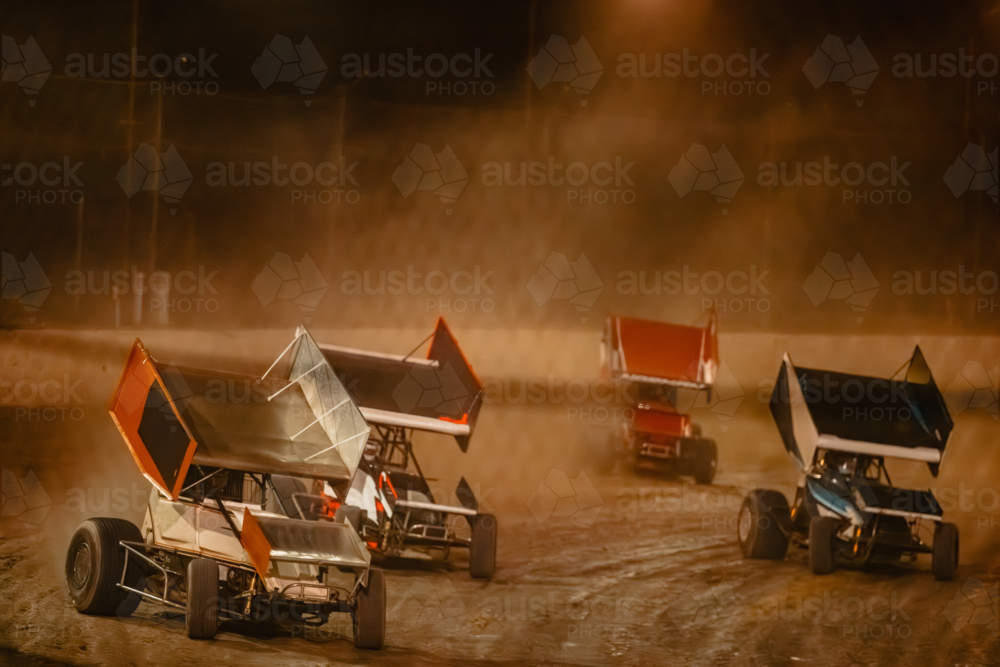 Image of Sprint cars race on a dirt track at night kicking up dust ...