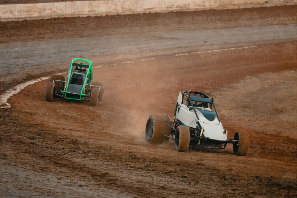 Image of Sprint cars race on a dirt track, kicking up dust as they ...