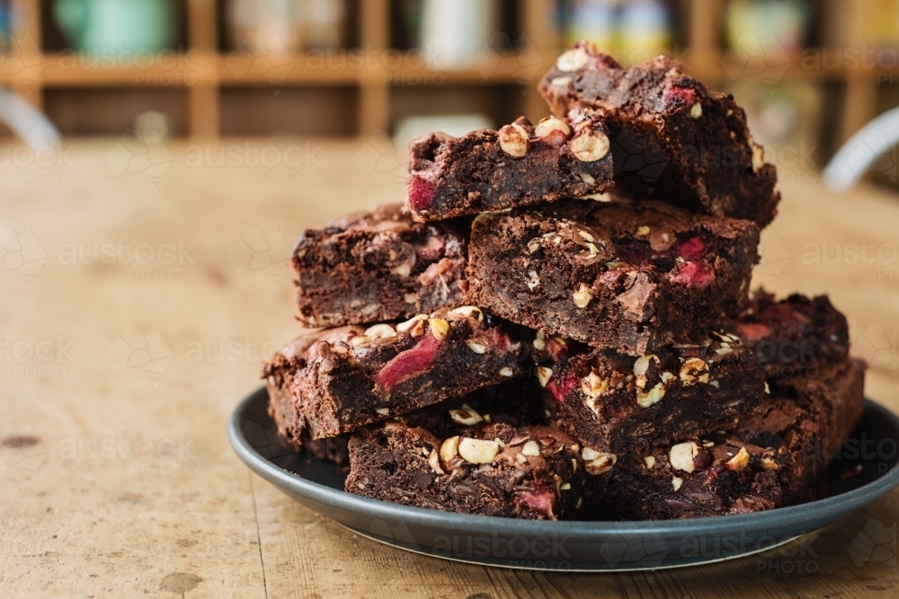 stack of freshly baked chocolate brownie with hazelnuts and strawberry - Australian Stock Image