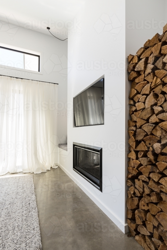 Stacked firewood alcove next to living room tv and fireplace - Australian Stock Image