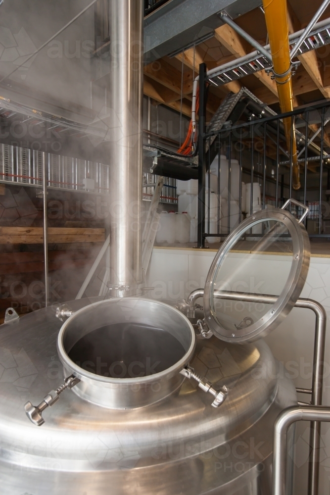 Stainless steel tank with steam escaping at a microbrewery - Australian Stock Image
