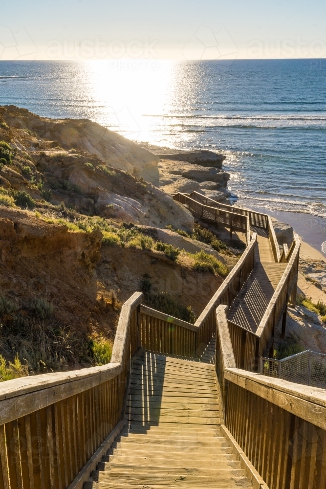 Stairs on a boardwalk leading around a cliff face in the sunshine - Australian Stock Image