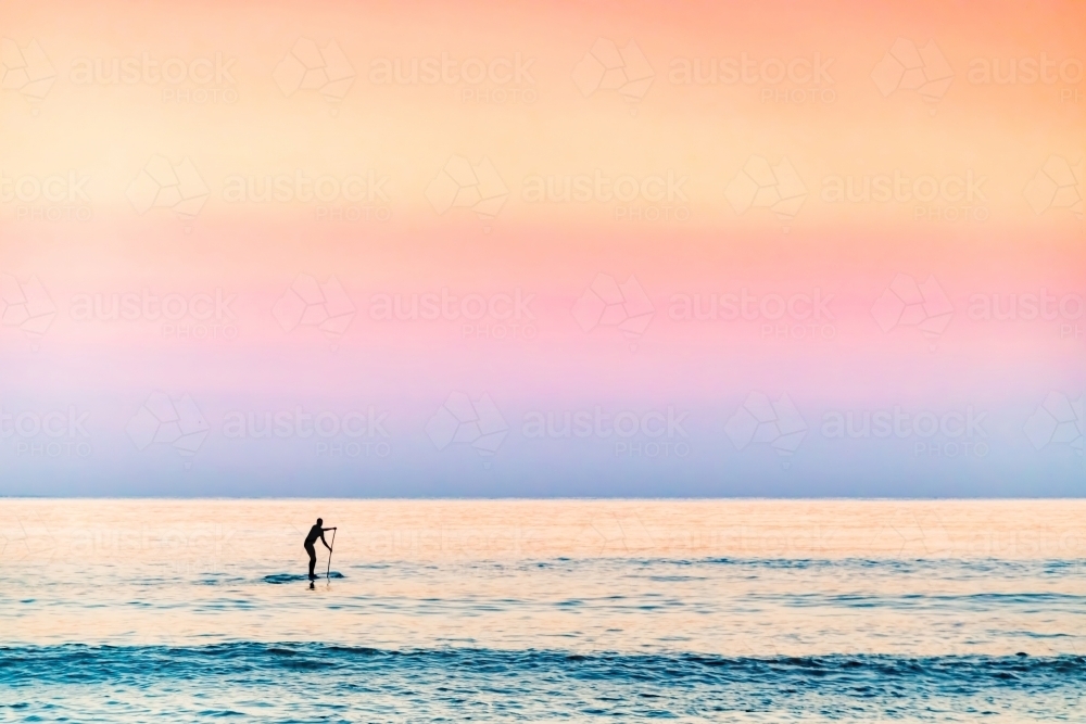 Stand up paddler in the ocean at dawn - Australian Stock Image