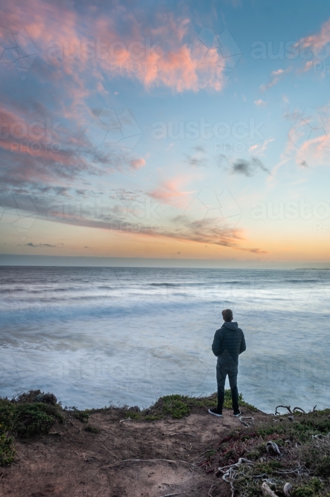 Man Standing on a Great Ocean Road Cliff at Sunset - Australian Stock Image