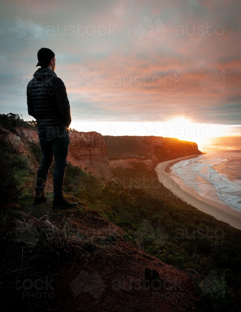 Man Standing on the Edge of a Great Ocean Road Cliff at Sunrise - Australian Stock Image