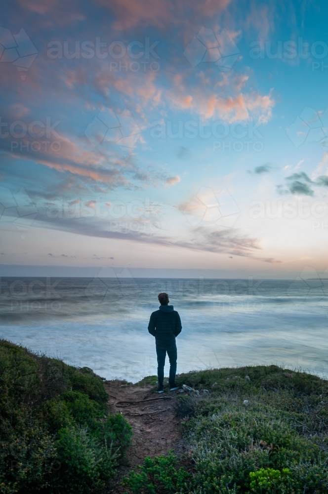Man Standing on the Edge of a Great Ocean Road Cliff At Sunset - Australian Stock Image