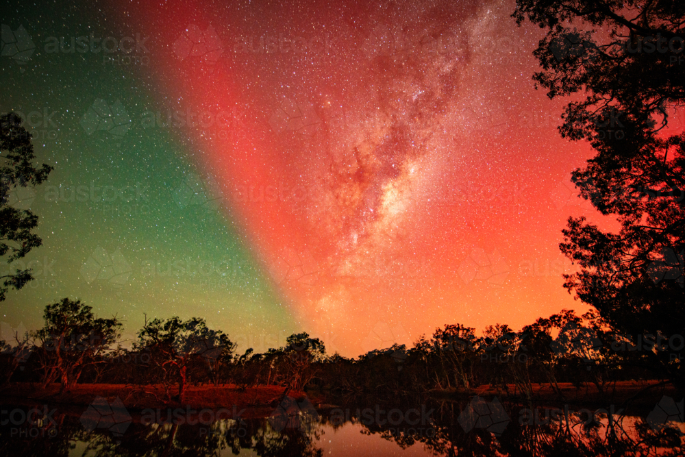 Image of Starry night sky painted in red and green aurora above ...