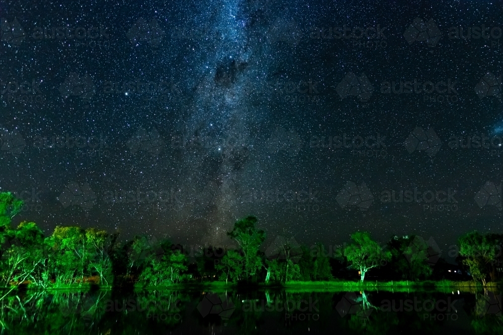 Starry night sky with Milky Way and reflections of trees in a lagoon - Australian Stock Image