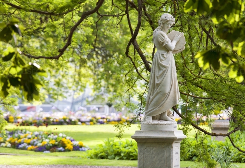 Statue in botanical gardens beneath green overhanging branches - Australian Stock Image