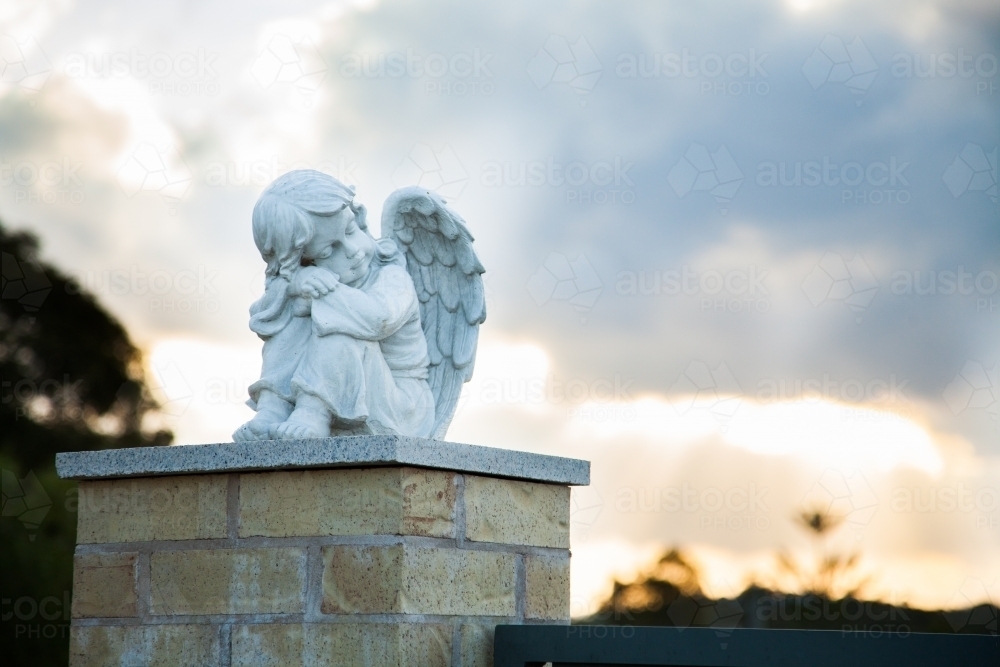 Statue of a angel girl against sunset sky - Australian Stock Image