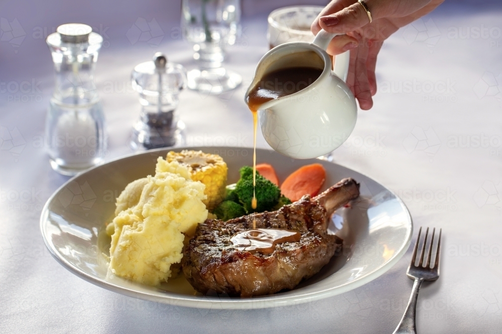 Steak dish with gravy being poured - Australian Stock Image