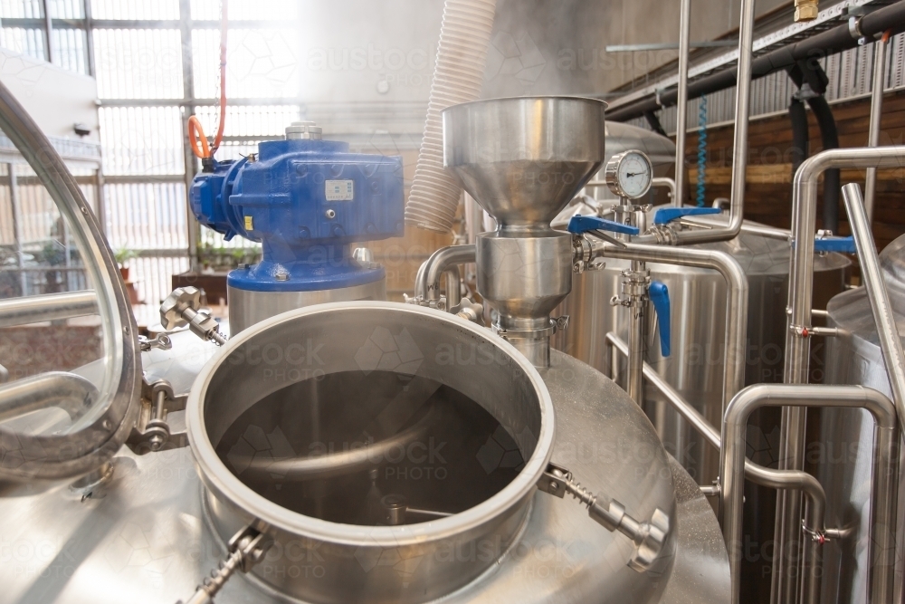 Steam escaping from hatch of a stainless steel tank at a microbrewery - Australian Stock Image