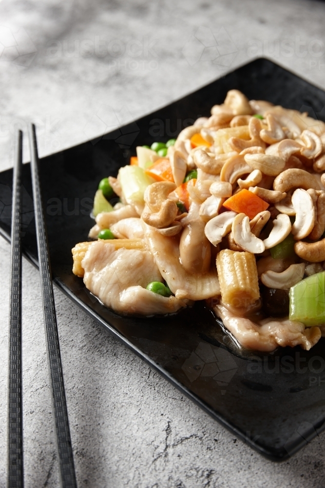Steamed chicken stir fry on black plate - Australian Stock Image