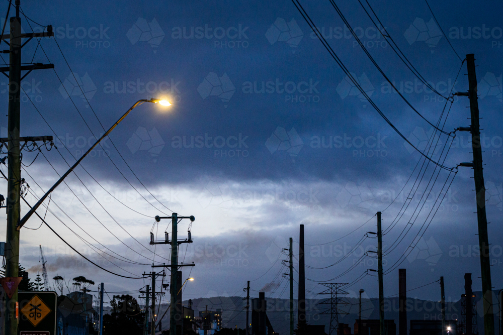 Steel smelter stacks behind silhouetted power lines - Australian Stock Image