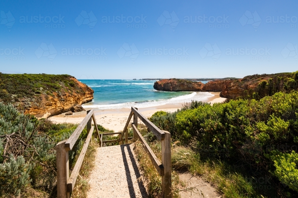 Steps down to sandy cove with headlands. blue sky and blue sea - Australian Stock Image