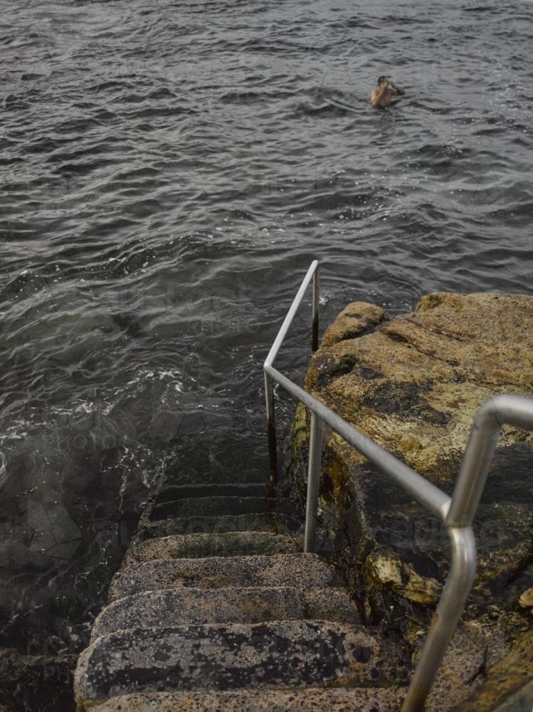 Steps leading down to sea and man swimming near Bronte Ocean pool - Australian Stock Image