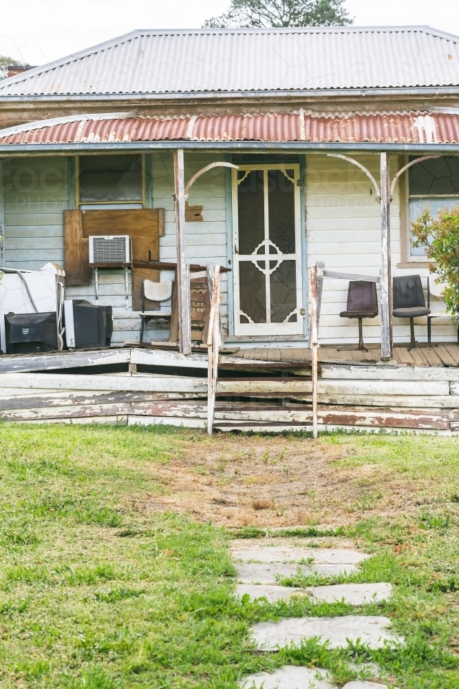 Steps leading up onto the verandah of a rundown weatherboard house - Australian Stock Image