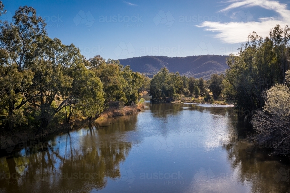 Still lake surrounded by mountains and trees - Australian Stock Image