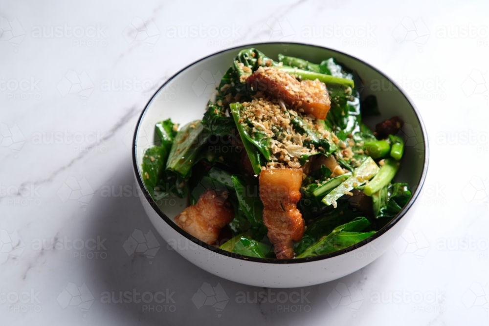 Stir-fried green leafy vegetable with pork belly slices garnished with crushed peanuts. - Australian Stock Image