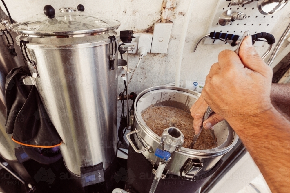 Stirring beer mash in a boiler - Australian Stock Image