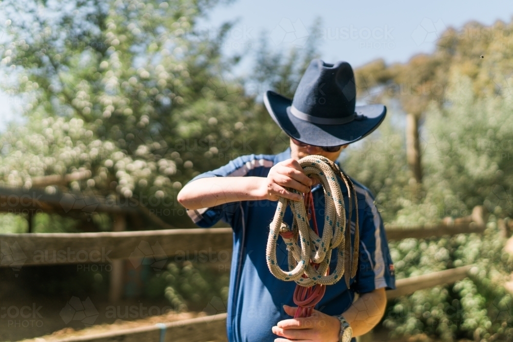 Stockman with Blue Hat Winding a Rope - Australian Stock Image