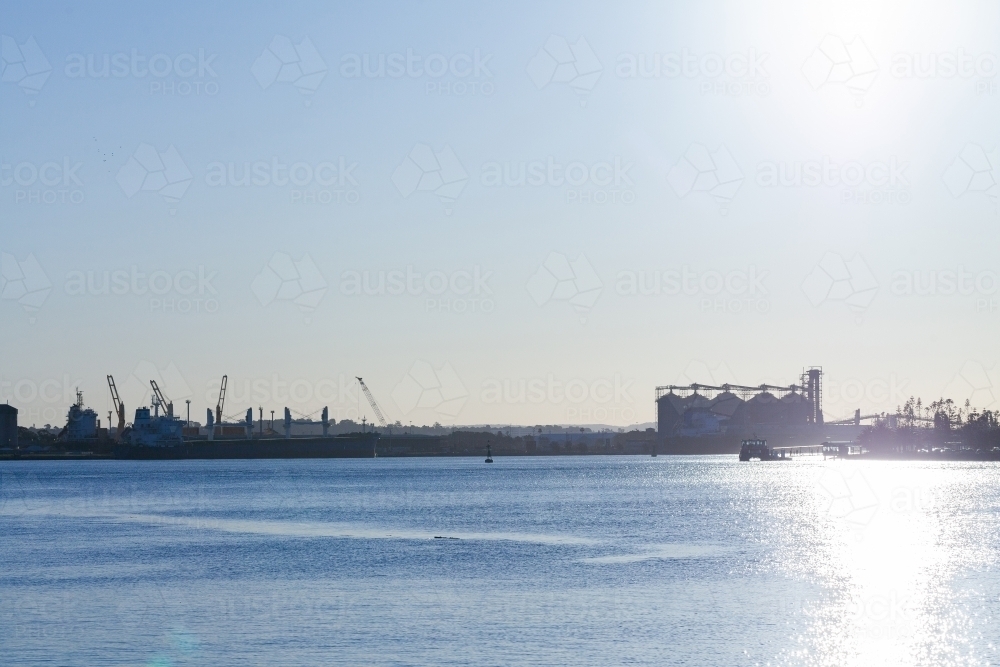 Stockton Wharf seen across blue water of Hunter river with silos behind - Australian Stock Image