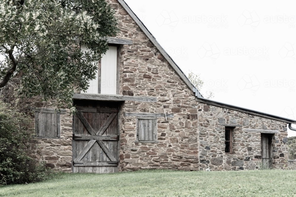 stone barn with wooden doors and shutters - Australian Stock Image