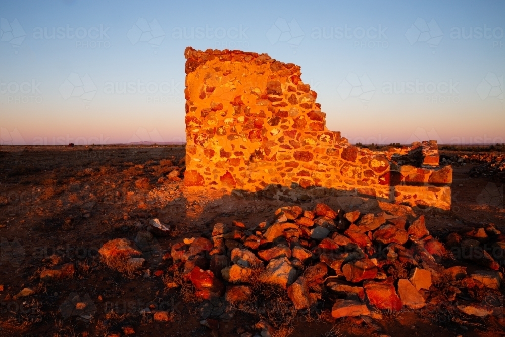 stone wall of ruin glowing in early morning light - Australian Stock Image