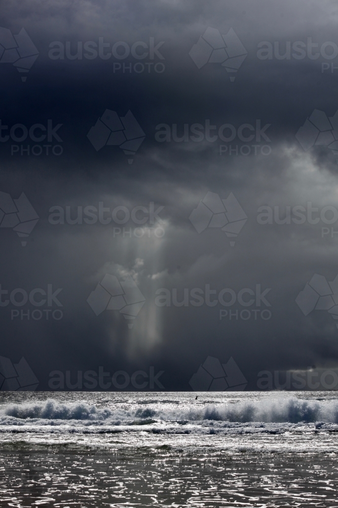 Storm behind ocean, surfer in distance, space above - Australian Stock Image
