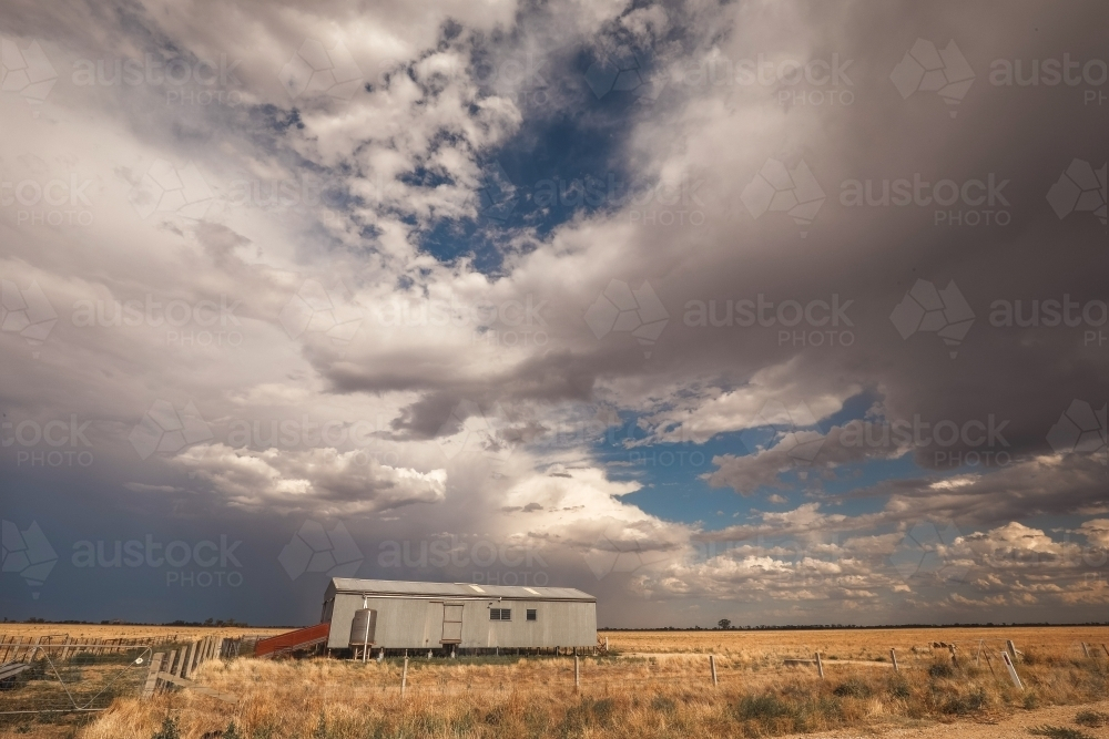 Storm brewing above shearing shed in a dry paddock in Central Victoria - Australian Stock Image
