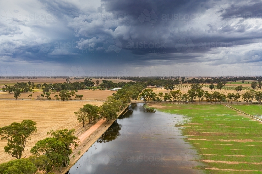 Storm clouds building over flooded farmland - Australian Stock Image
