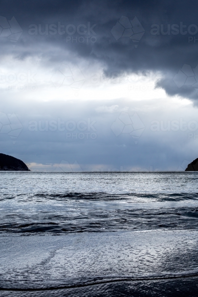 Storm clouds darken the sky over a beach - Australian Stock Image